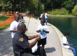 Officer Sam Anderson showing a child the proper way to put a worm on a hook.