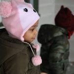 A child wearing a hat gazes in wonder at her new living space.