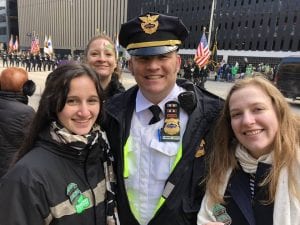 An officer poses outside with three young women.