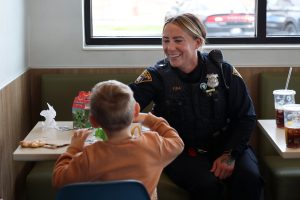 A CPD officer chats with a young boy enjoying a Happy Meal during Coffee with a Cop.