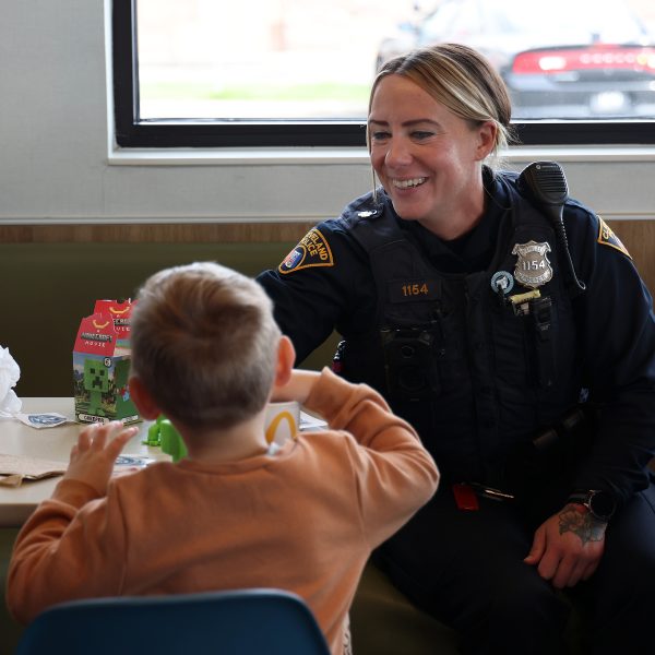A CPD officer chats with a young boy enjoying a Happy Meal during Coffee with a Cop.