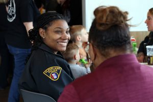 A CPD officer smiles while speaking with a resident at a crowded table filled with families.