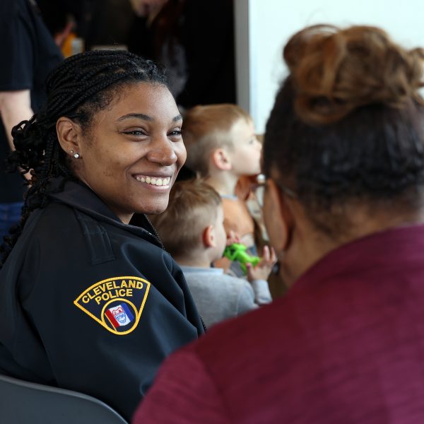 A CPD officer smiles while speaking with a resident at a crowded table filled with families.