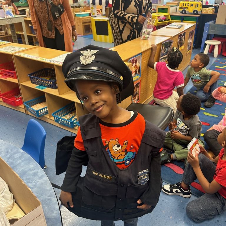 Grinning student stands proudly in oversized police gear.