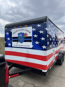 A custom-wrapped Police Unity Tour trailer featuring stars, stripes, and the slogan “We Ride for Those Who Died.”