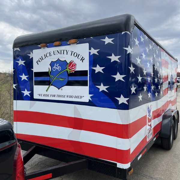 A custom-wrapped Police Unity Tour trailer featuring stars, stripes, and the slogan “We Ride for Those Who Died.”