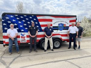 Five men pose in front of the trailer, including officers, supporters, and CPF’s Bob Guttu.