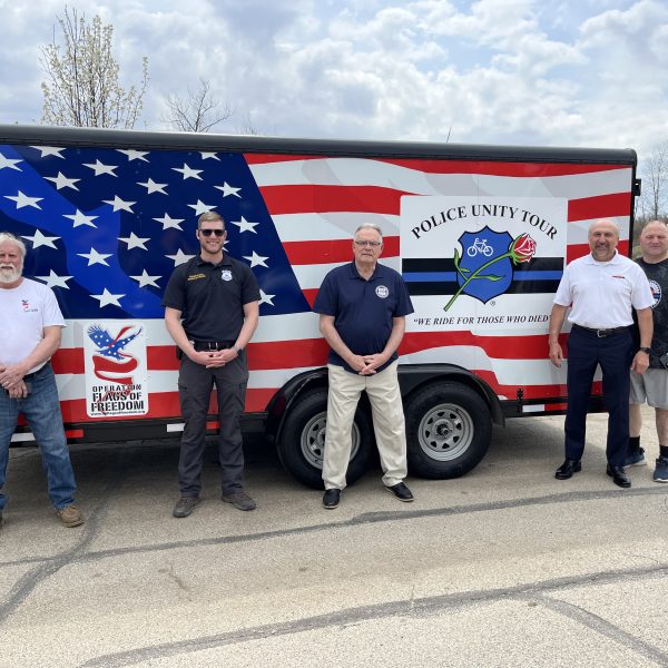 Five men pose in front of the trailer, including officers, supporters, and CPF’s Bob Guttu.