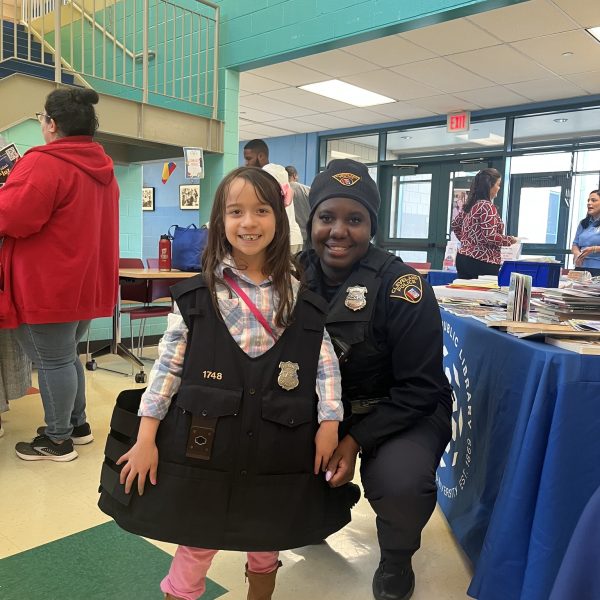 Officer Lavender kneels beside a young girl proudly wearing CPD gear