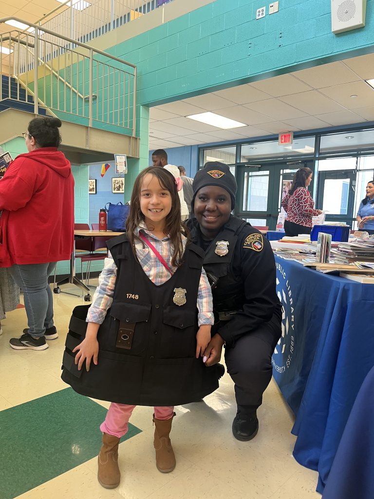 Officer Lavender kneels beside a young girl proudly wearing CPD gear