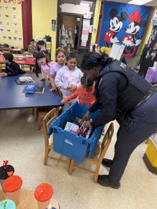 Officer Lavender hands out school supplies from a blue bin while students gather around her at Scranton Elementary.