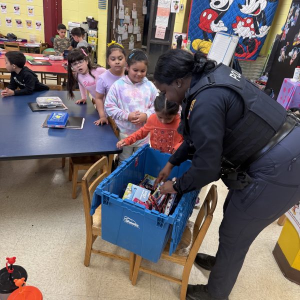 Officer Lavender hands out school supplies from a blue bin while students gather around her at Scranton Elementary.