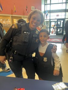 Officer Simpson smiles with a young student wearing a CPD vest at Buhrer Elementary