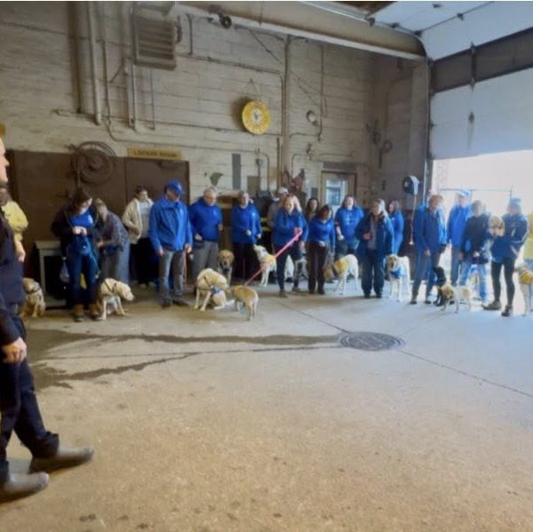 A Mounted Unit officer welcomes a large group of Canine Companions visitors inside the stables.