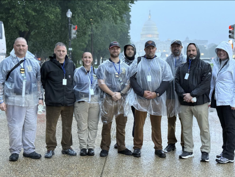 A group of Cleveland officers wearing ponchos and jackets pose near the U.S. Capitol during a rainy National Police Week in Washington, DC
