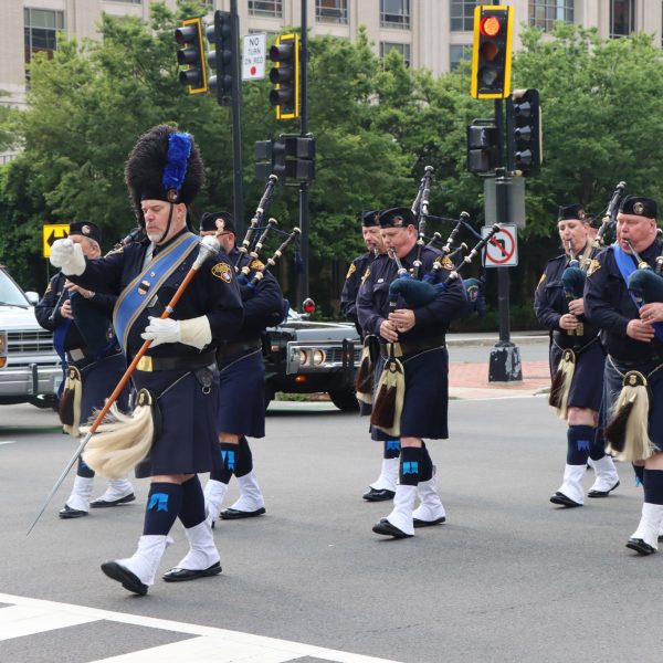 Cleveland Police Pipes and Drums march in formation along a city street during the NCLEES Memorial March