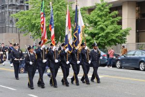 Honor Guard continues down the parade route with flags raised and Pipes and Drums following close behind