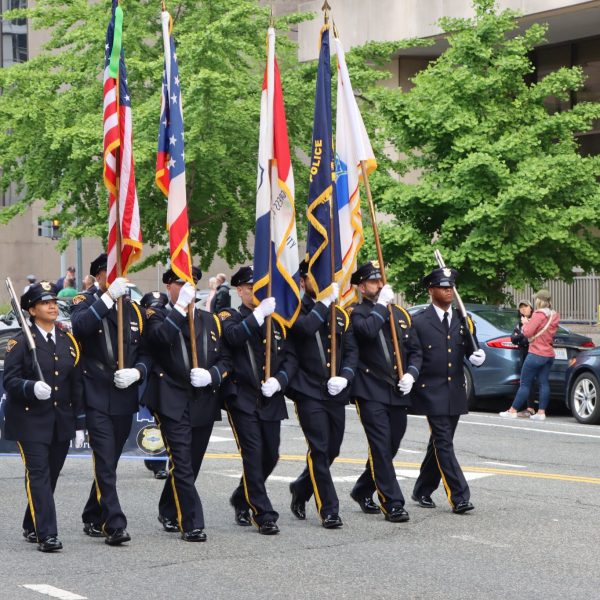 Honor Guard continues down the parade route with flags raised and Pipes and Drums following close behind