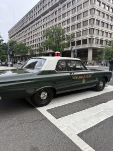 Vintage patrol car marked “Greenwich Police” crosses a Washington, D.C. intersection during the memorial parade
