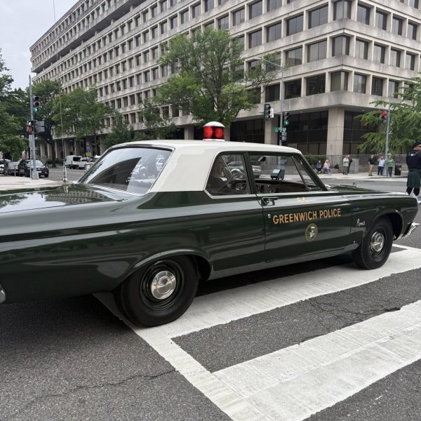 Vintage patrol car marked “Greenwich Police” crosses a Washington, D.C. intersection during the memorial parade