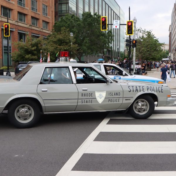 Vintage Rhode Island State Police cruiser crosses an intersection during the NCLEES Memorial March