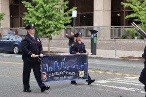 Two CPD officers carry the Cleveland Police Pipes and Drums banner during the parade