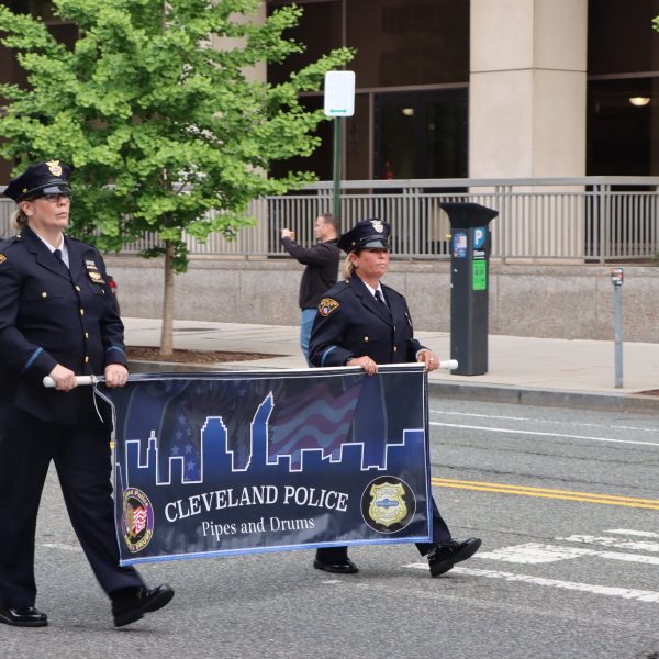 Two CPD officers carry the Cleveland Police Pipes and Drums banner during the parade