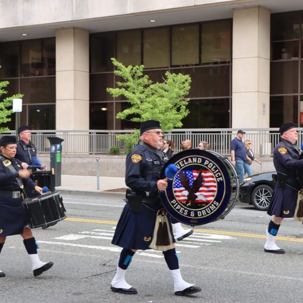 Drumline and pipers from the Cleveland Police Pipes and Drums continue down a city street