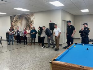 Bob Guttu shares a hug with a Hispanic Senior Center staff member while CPD officers and other staff look on and applaud during the award event