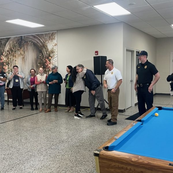 Bob Guttu shares a hug with a Hispanic Senior Center staff member while CPD officers and other staff look on and applaud during the award event