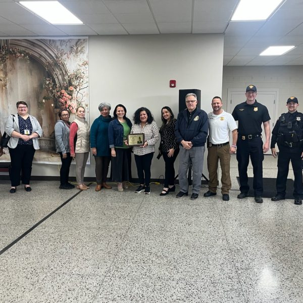 Group photo of CPD Second District officers with staff and members of the Hispanic Senior Center, including Commander Maffo-Judd and Bob Guttu, holding a Community Partner of the Month plaque