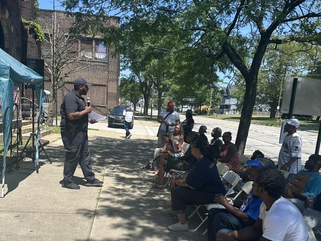 Big H Block Party Speaker addresses seated guests under a tent in front of The Lion Church during the block party